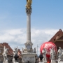 Plague Column. The original monument was built in 1681; the current one is a 1743 replacement by local sculptor Jožef Štraub. It is considered among his finest work, and one of the best examples of baroque art in Slovenia. It is made entirely of white marble, and consists of an ornate rectangular pedestal that supports a Corinthian column bearing a gilded statue of the Virgin Mary, crowned with twelve stars and standing on the moon (a reference to Revelation 12:1). At its base, the column is surrounded by six saints to whom the townspeople had prayed for intercession.