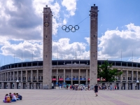 Olympic Stadium  The Olympiastadion was originally built for the 1936 Summer Olympics by Werner March. During the Olympics, the record attendance was thought to be over 100,000. Today the stadium is part of the Olympiapark Berlin. When the Nazis came to power in Germany (1933), they decided to use the Olympic Games in 1936 for propaganda purposes. With these plans in mind, Adolf Hitler ordered the construction of a great sports complex in Grunewald named the "Reichssportfeld" with a totally new Olympiastadion. Architect Werner March remained in charge of the project, assisted by his brother Walter. Construction took place from 1934 to 1936. When the Reichssportfeld was finished, it was 1.32 square kilometres. It consisted of (east to west): the Olympiastadion, the Maifeld (Mayfield, capacity of 50,000) and the Waldbühne amphitheater (capacity of 25,000), in addition to various places, buildings and facilities for different sports (such as football, swimming, equestrian events, and field hockey) in the northern part. : 2016, Berliini, Berlin, Fujifilm, Germany, Saksa, digital image, historia, history, kaupunki, kesäloma, matka, summer holiday, town, travel