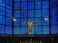 Kaiser-Wilhelm-Gedächtnis-Kirche  The plan of the church is octagonal while the plan of the tower is hexagonal. These components are sited on a plateau measuring 100 metres long and 40 metres wide. The new buildings are constructed of concrete, steel and glass. The walls of the church are made of a concrete honeycomb containing 21,292 stained glass inlays. The glass, designed by Gabriel Loire, was inspired by the colours of the glass in Chartres Cathedral. The predominant colour is blue, with small areas of ruby red, emerald green and yellow. The church is 35 metres in diameter and 20.5 metres high with a capacity of over 1,000. Inside the church, opposite the entrance, is a figure of Christ which is suspended above the altar. This is made from tombak and was designed by Karl Hemmeter. The cross on the altar, by Peter Tauchnitz, is of gilt silver with 37 rock crystals. To the left of the altar is the baptismal font on a stand filled with Carrara marble which contains a majolica bowl for the holy water. To the right of the altar is an octagonal pulpit : 2016, Berliini, Berlin, Germany, LG, Saksa, kaupunki, kesäloma, mobile phone, summer holiday, town