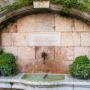 Fish spout at old fountain beneath gothic Stadtpfarrkirche St. Jakob.